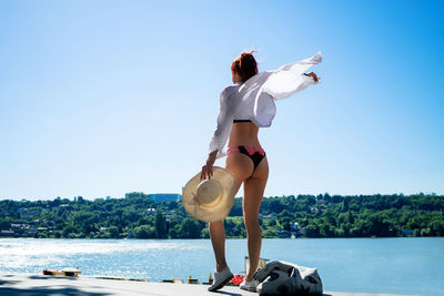 Rear view of carefree woman at the beach against the sky during summer day. copy space.