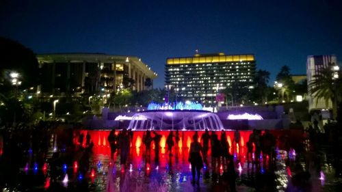 Crowd at illuminated city against sky at night