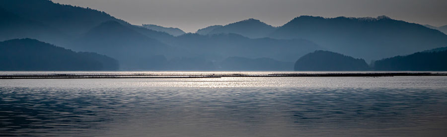 Scenic view of sea and mountains against sky