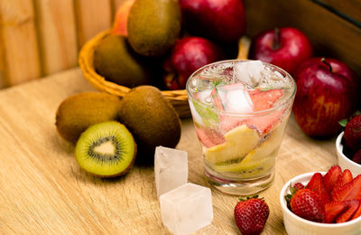 Detox water fruit with apple wiki strawberry and ice in glass on wood background