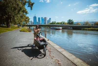 Rear view of woman sitting on bench against sky