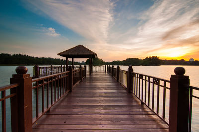 Jetty in lake against sky during sunset