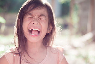 Girl with eyes closed screaming outdoors