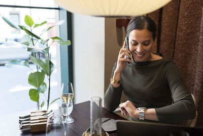 Woman in restaurant talking via cell phone and checking time