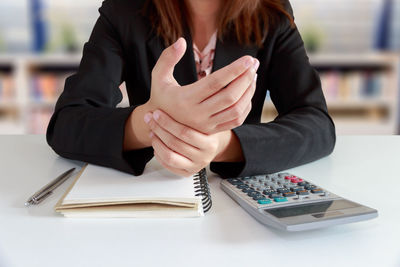 Midsection of woman sitting on table