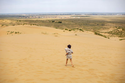 Boy is child traveler in a suit of an archaeologist tracker and wearing hat walk sand in the desert