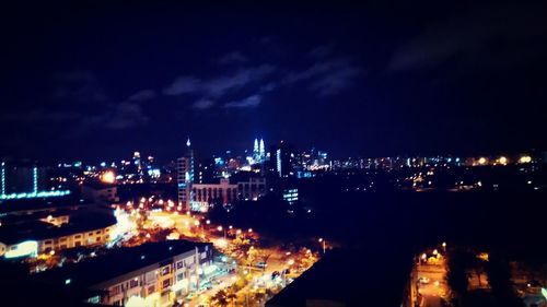 Illuminated cityscape against sky at night