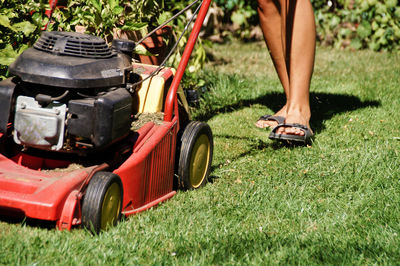 Low section of woman with lawn mower on field