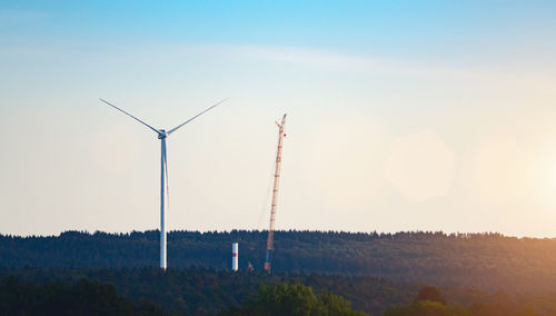 Wind turbines on landscape against sky