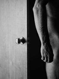 Low section of naked man standing by door at home