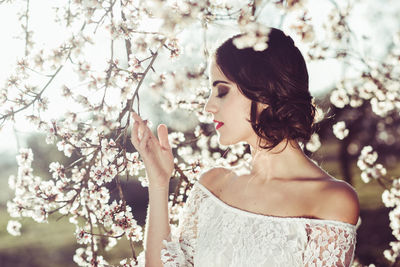 Young woman touching almond flower blossom