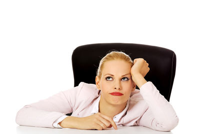 Portrait of young woman sitting against white background