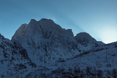 Low angle view of snowcapped mountains against clear blue sky