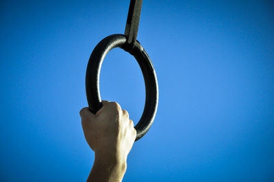 Close-up of hand holding metal against clear blue sky