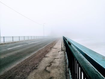 Empty road by bridge against sky