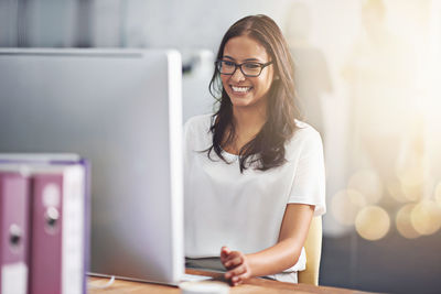 Portrait of young woman using mobile phone while sitting at home