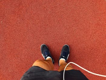 Low section of person standing by red shoes