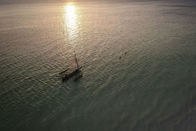 Aerial view of sailboat on sea during sunset