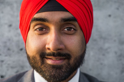 Close-up portrait of businessman wearing turban standing against wall