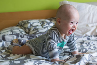 Cute baby boy looking away lying on bed at home