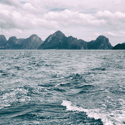 Scenic view of sea by mountains against sky