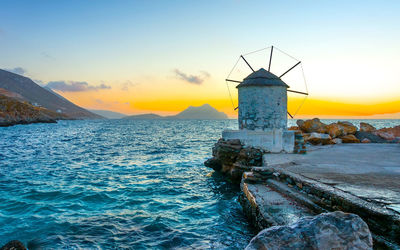 Lighthouse by sea against sky during sunset