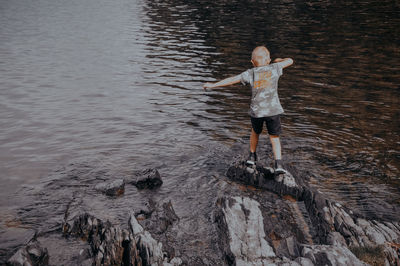 View of siblings on rock at beach