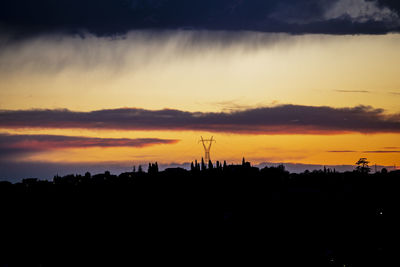 Silhouette landscape against dramatic sky during sunset