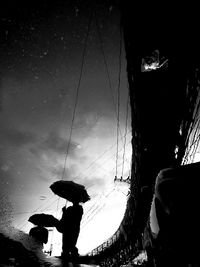 Silhouette people in rain against sky during rainy season