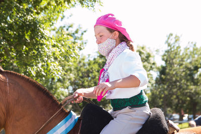 Argentinian girl riding horse and wearing face mask