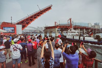 People at town square by sea against sky