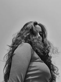 Low angle view of young woman against sky