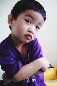 Portrait of cute boy with arms crossed against wall at home