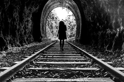 Rear view of man walking on railroad track