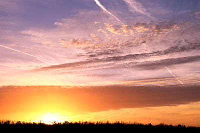 Low angle view of vapor trails in sky during sunset