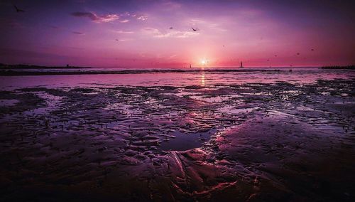 Scenic view of sea against dramatic sky during sunset