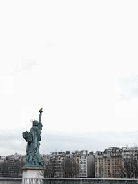 Statue in city against clear sky