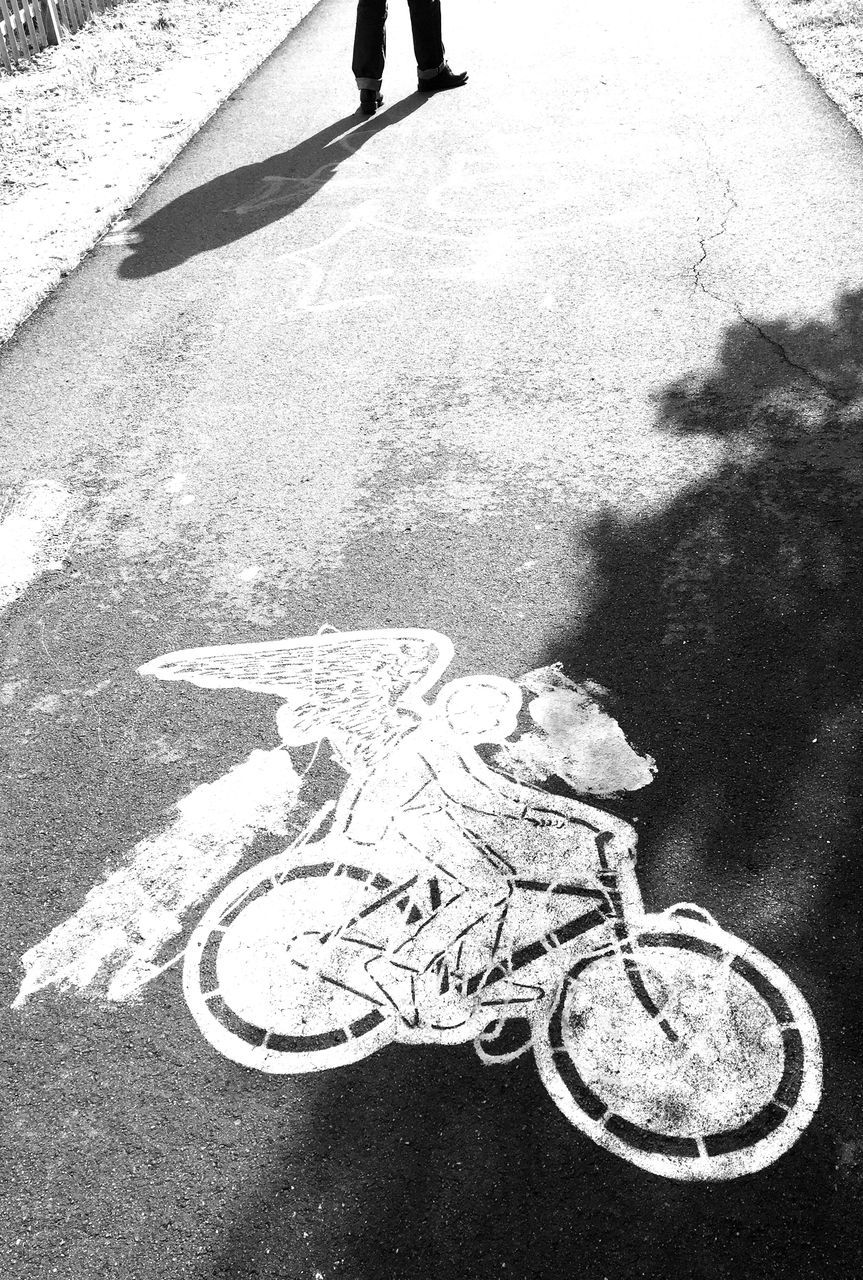 high angle view, street, road marking, asphalt, road, transportation, communication, shadow, guidance, text, bicycle, outdoors, western script, day, road sign, low section, unrecognizable person, sign