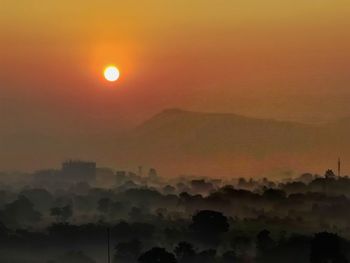 Scenic view of silhouette mountains against orange sky