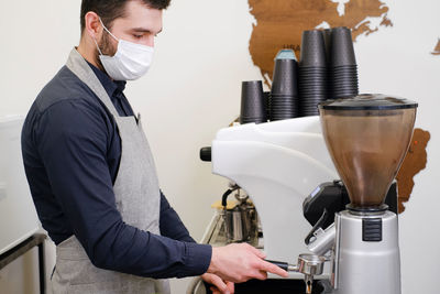 Barista serving coffee in takeaway cups in coffee shop in protective mask. coffee to go during