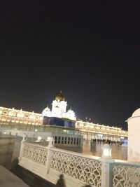 Illuminated buildings in city against clear sky at night