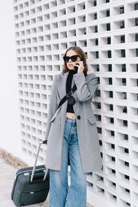 Young woman wearing sunglasses standing against brick wall