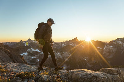 Adventurous man hiking along mountain ridge during sunset.