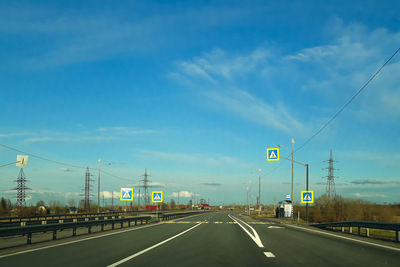 Road sign on highway against sky