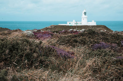 Lighthouse by sea against sky