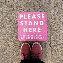 Low section of man standing on social distancing sign 