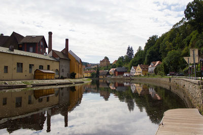 Arch bridge over river amidst buildings against sky