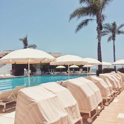 Lounge chairs by swimming pool at beach against clear sky