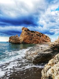 Rock formation on beach against sky