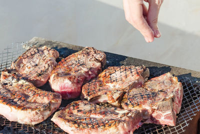 The meat is grilled. cooks hand salt steaks in a barbecue.